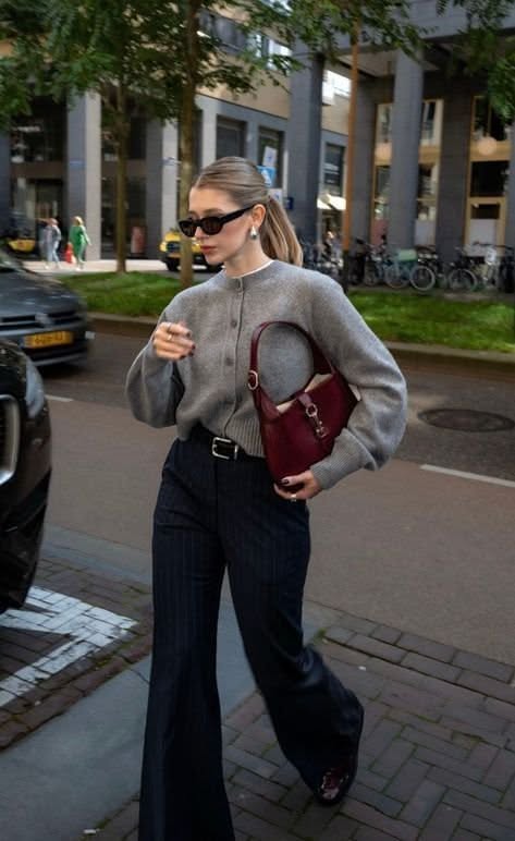 Woman in a grey cardigan and flared pants walking on a city street