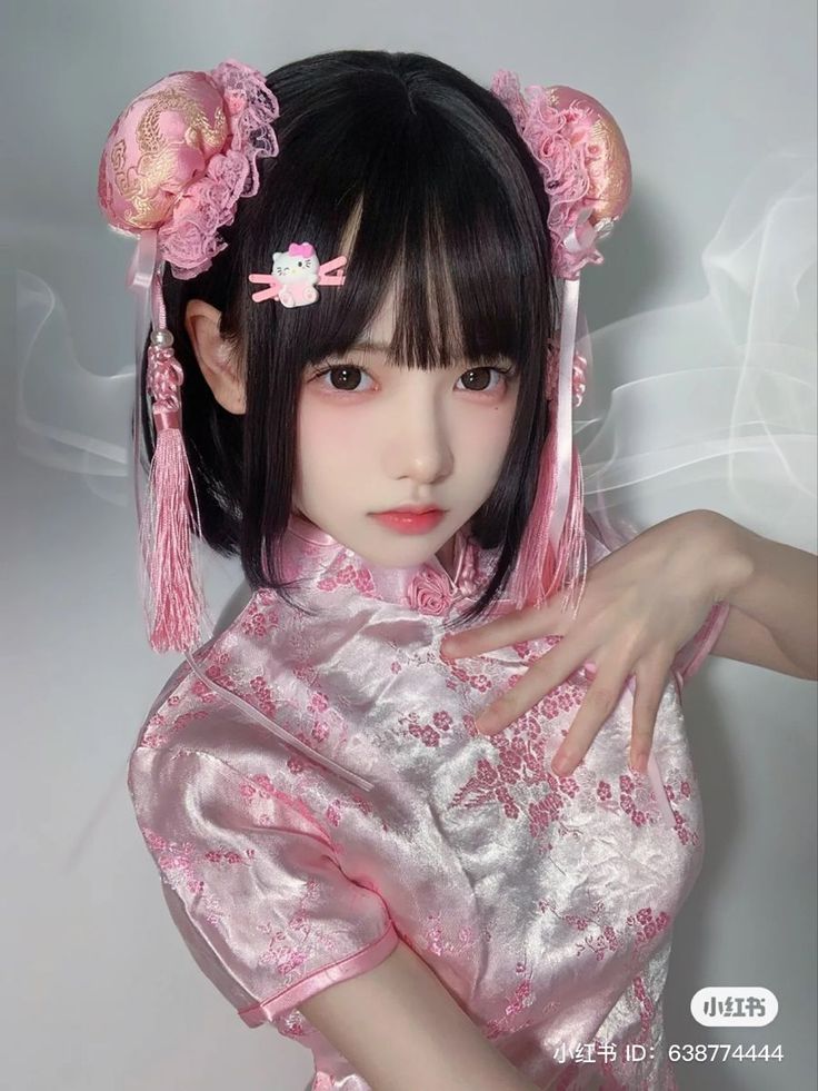 Person in a pink cheongsam with hair buns and pink tassels