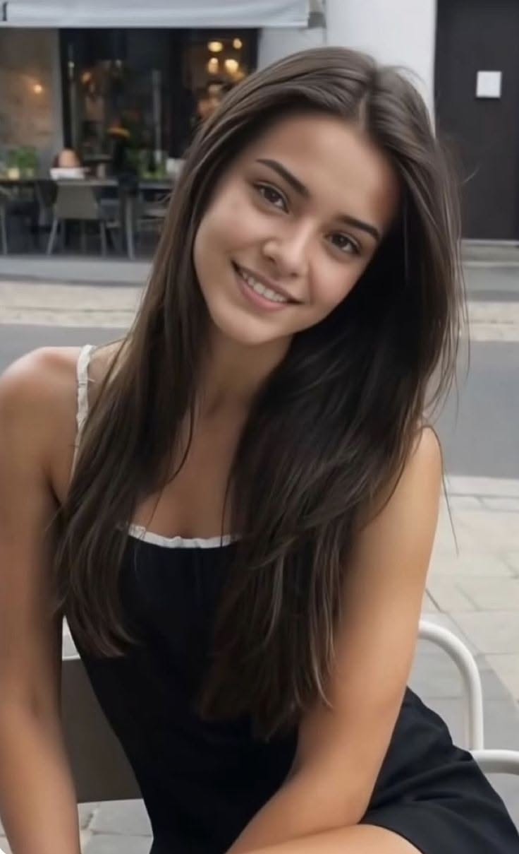 Smiling woman with long brown hair wearing a black dress outdoors