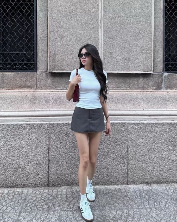 Woman with long dark hair wearing a white t-shirt and mini skirt on a street