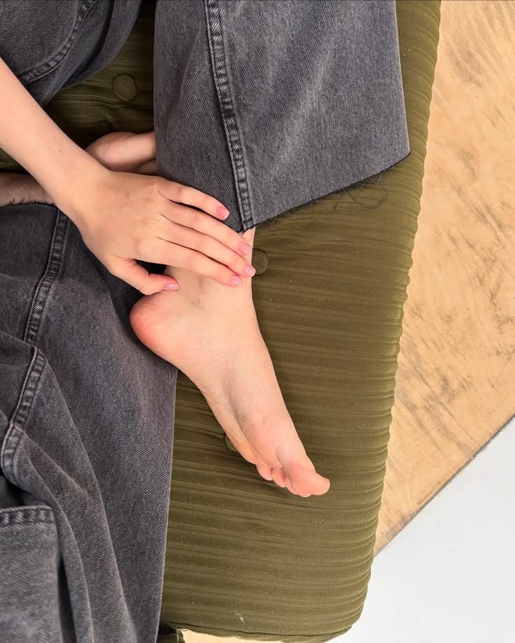 Close up of a bare foot and hand on green fabric with denim jeans