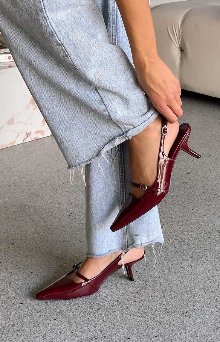 Person wearing red slingback heels and light wash jeans with a frayed hem