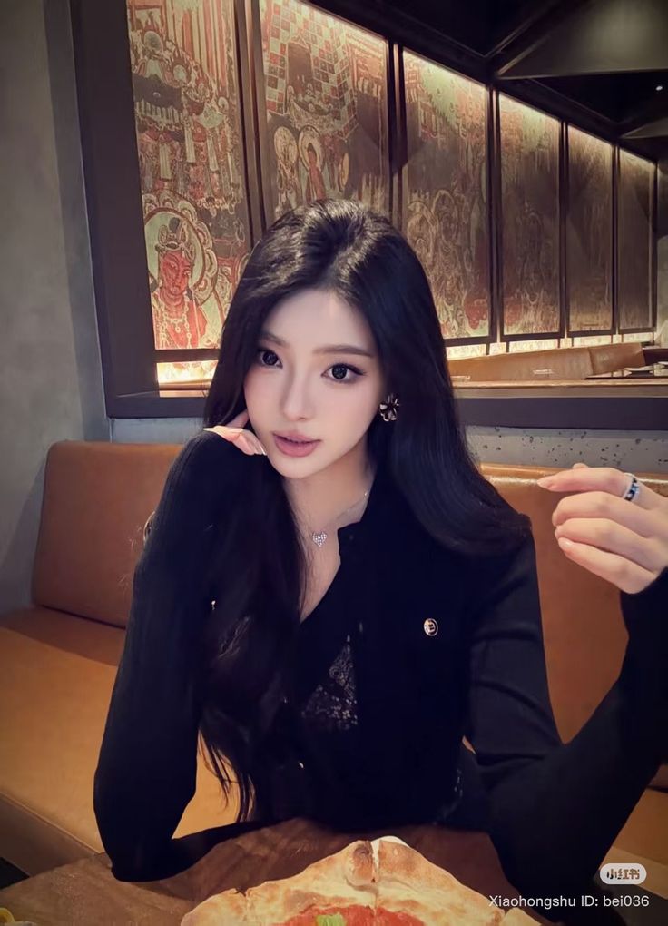 Woman with long black hair wearing a black top in a restaurant