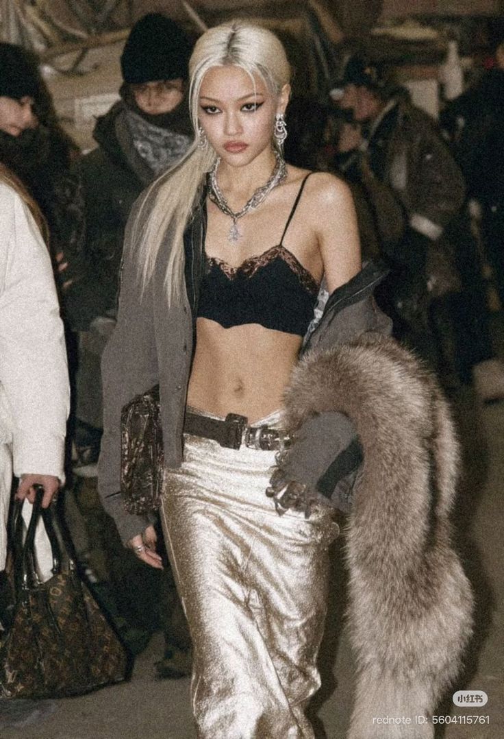 Woman with long blonde hair in a black bralette and metallic pants