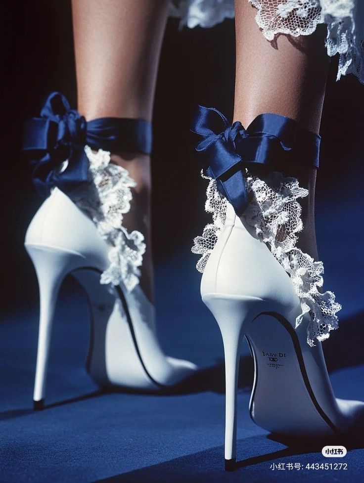 White high heels with blue ribbon and lace detail on a dark blue background