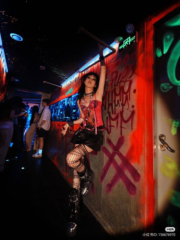 Person in gothic attire with fishnet stockings and platform boots in a neon-lit nightclub