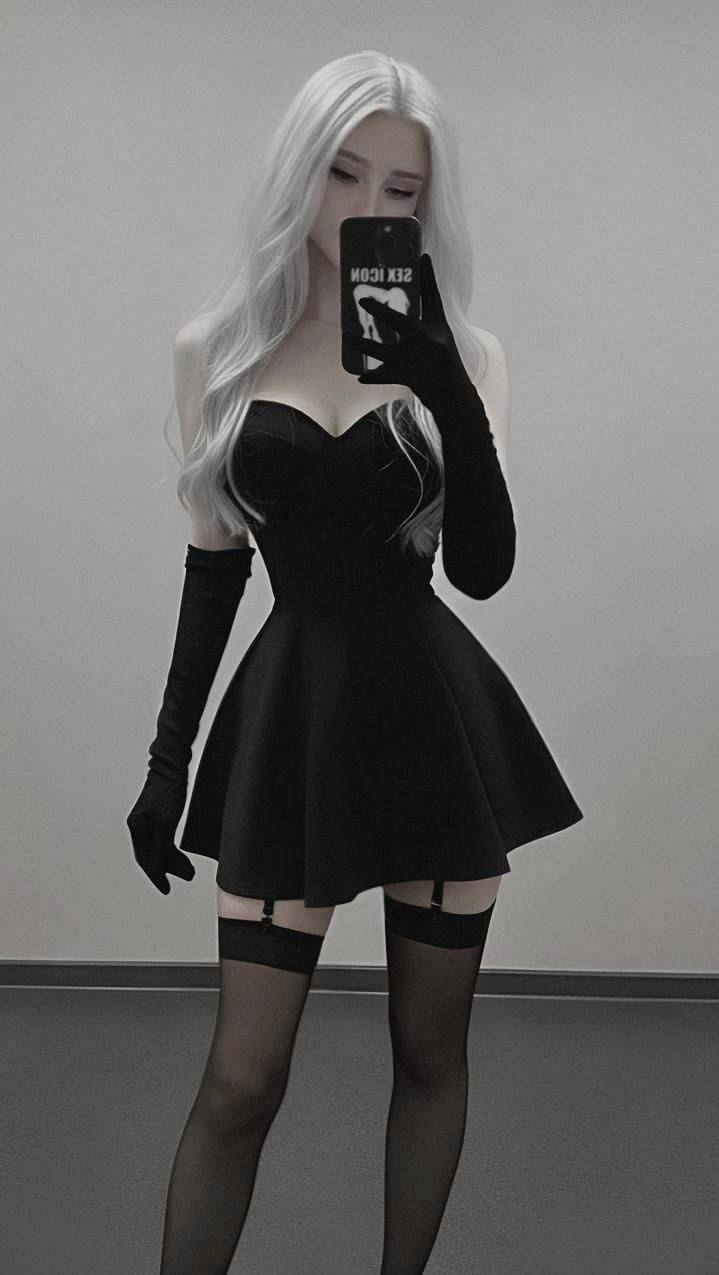 Woman with long white hair in a black dress and stockings taking a mirror selfie