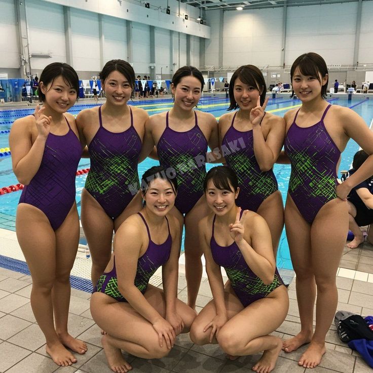 Group of women in purple and green swimsuits posing by a swimming pool