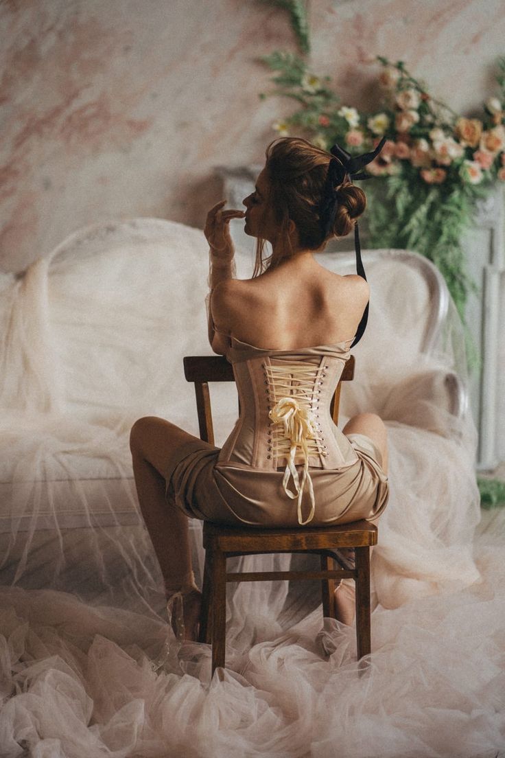 Woman in a corset with exposed back sitting on a chair indoors