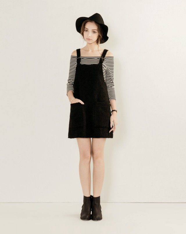 Woman in a black hat and overalls dress with a striped shirt