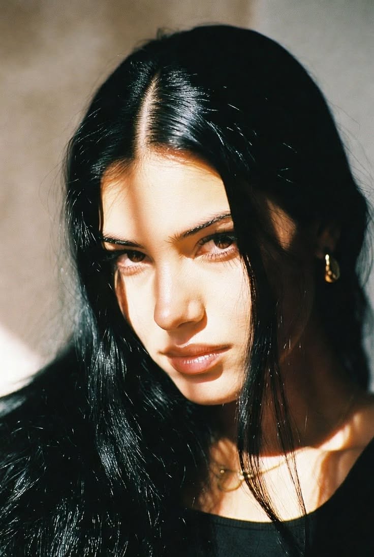Woman with long black hair in dramatic lighting with shadows on her face