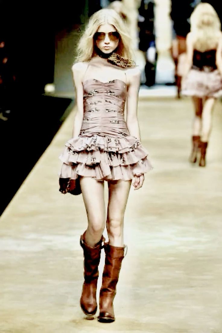 Blonde model in a mini dress and boots walking on a runway