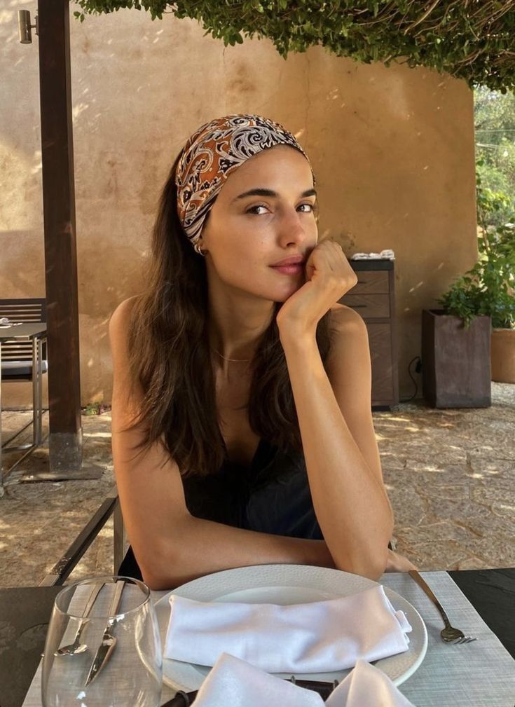 Woman with a patterned headband sitting at an outdoor dining table