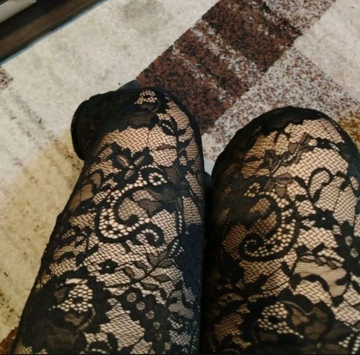 Close up of legs wearing black lace stockings on a patterned carpet