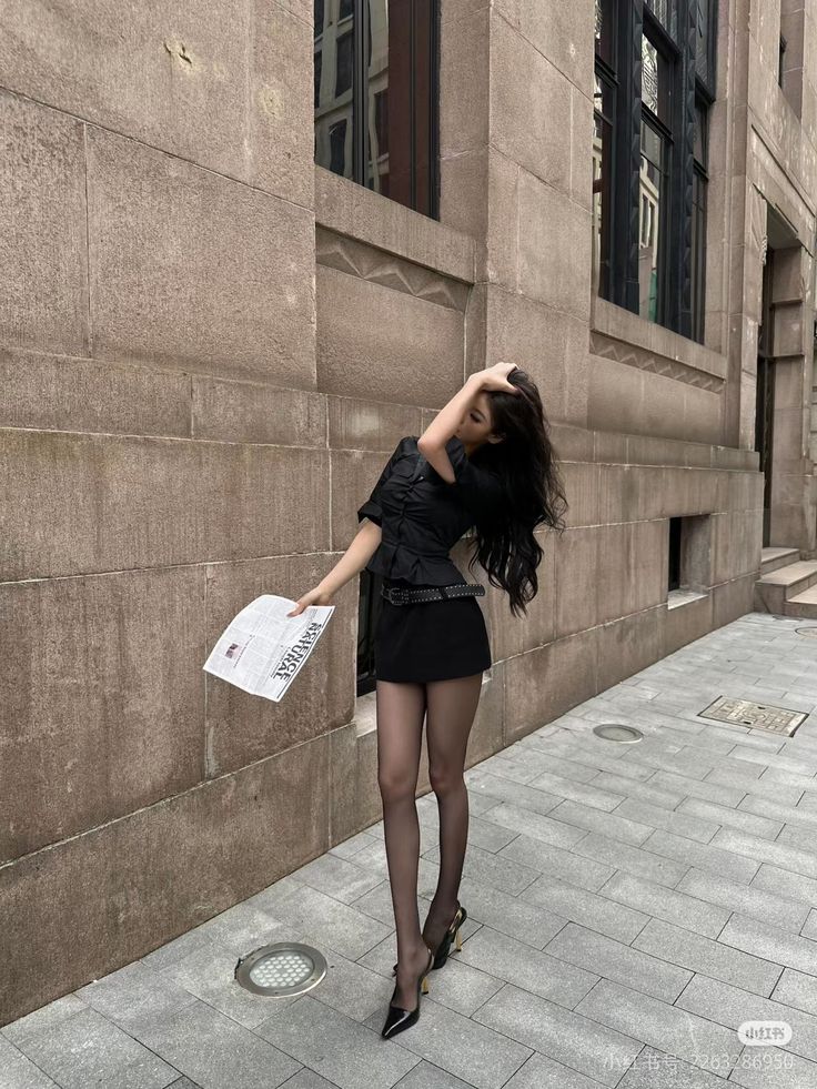 Woman in a black mini skirt and tights posing on a city street