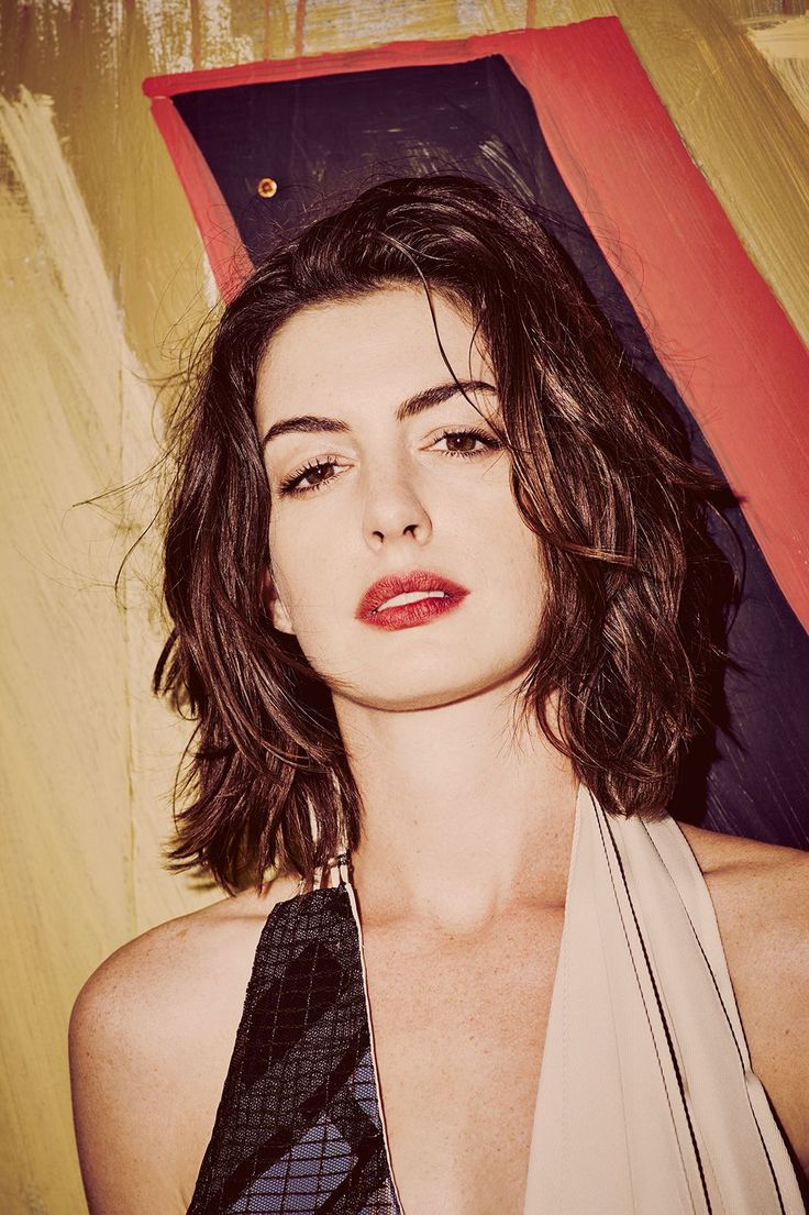Woman with short brown hair and red lipstick against a painted background