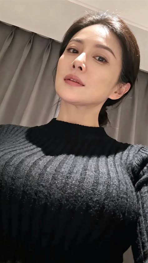 Woman with dark hair wearing a black sweater indoors