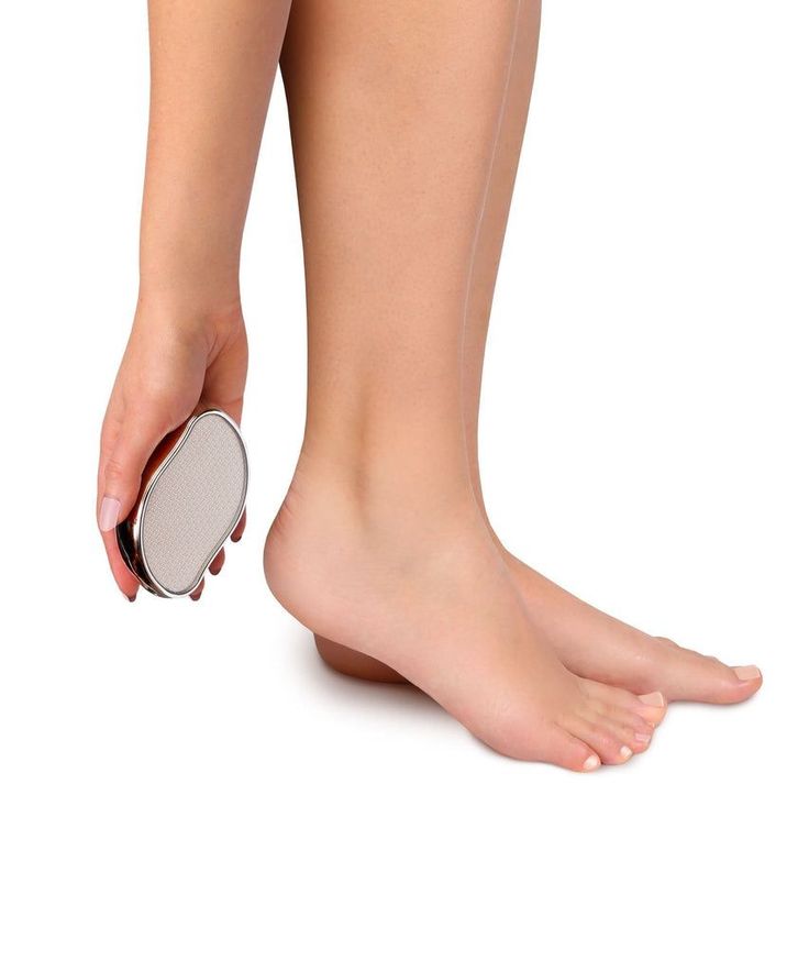 Person holding a foot file next to bare feet on a white background