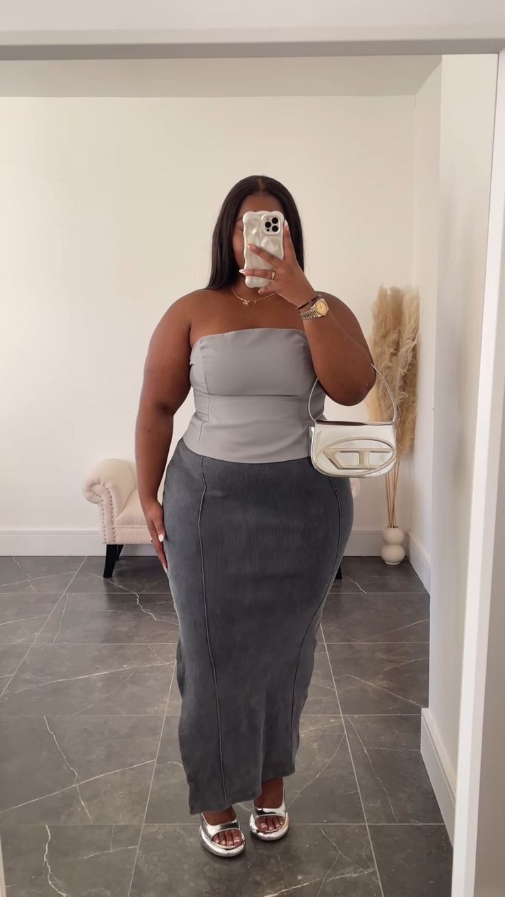 Woman in a strapless top and maxi skirt taking a mirror selfie