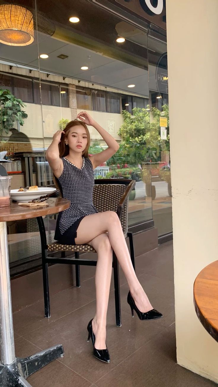 Woman in a black dress and high heels sitting at a cafe table