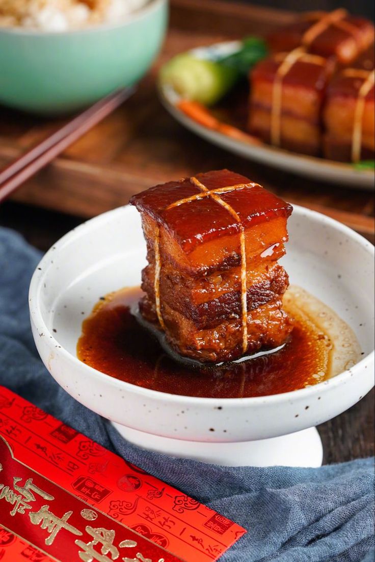 Braised pork belly in a white bowl with sweet sauce