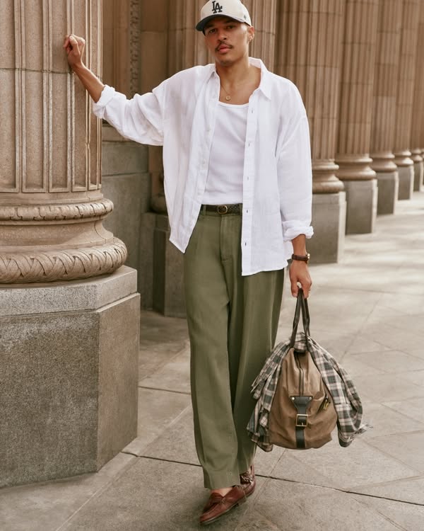 Man in a white shirt and olive pants leaning against a column