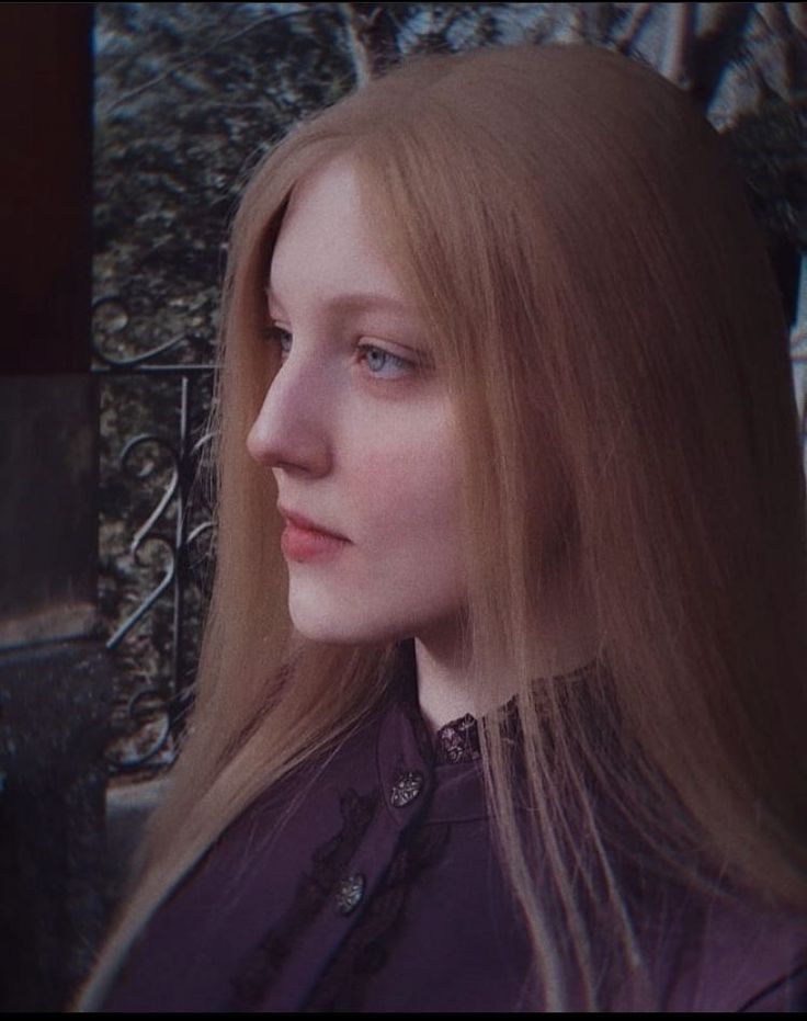 Woman with long blonde hair and blue eyes in a purple shirt with a lace collar