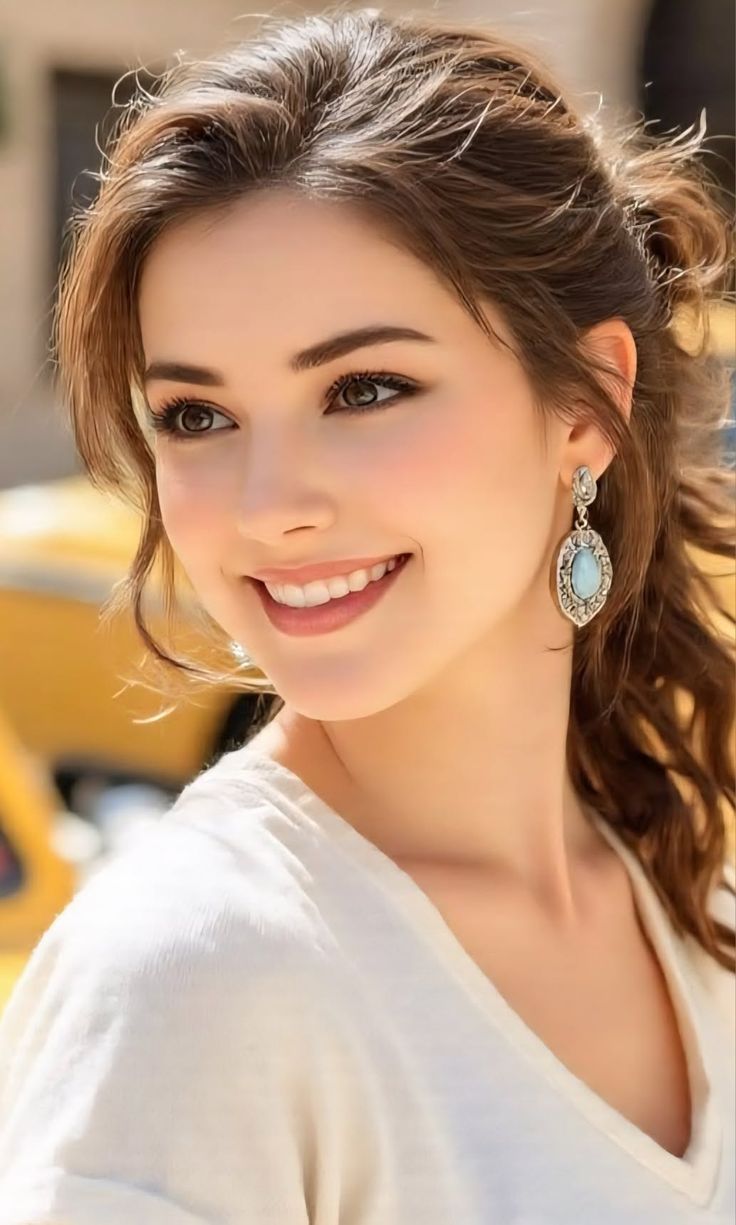 Woman with long brown hair and earrings smiling in soft lighting