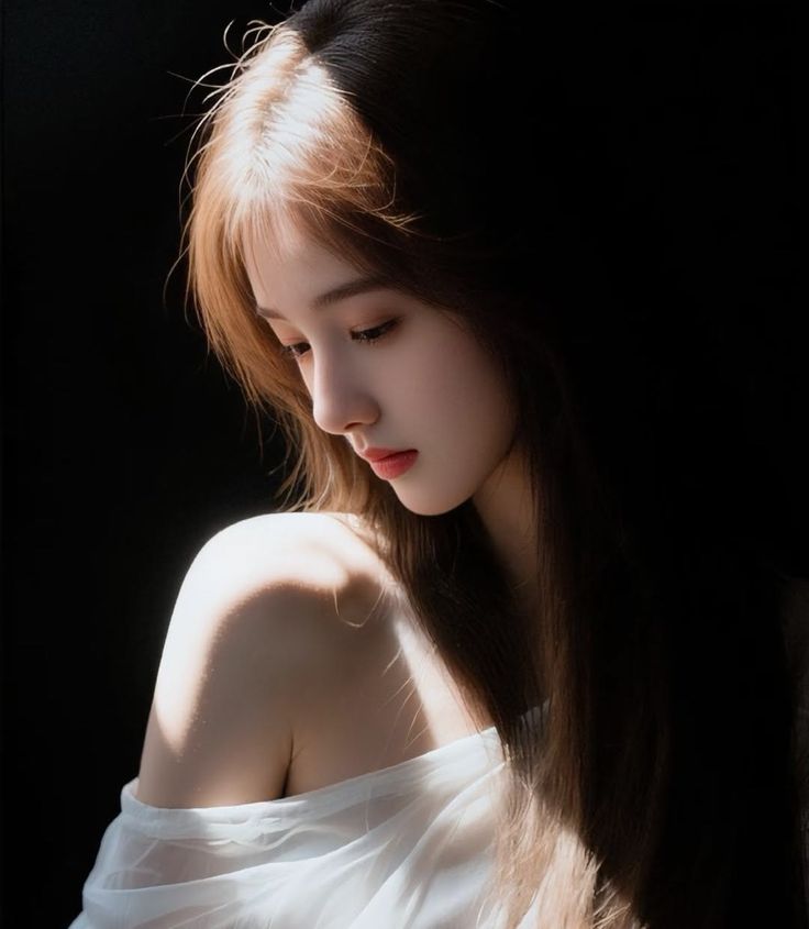 Woman with long hair and a white top, illuminated by dramatic lighting