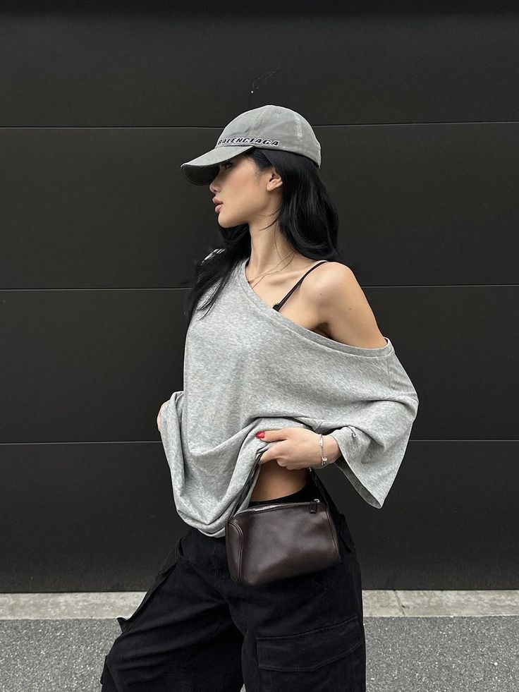 Woman in a grey off-shoulder top and black cargo pants with a small handbag