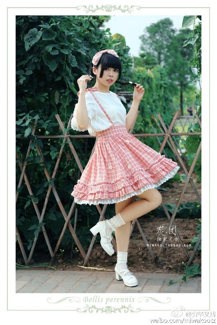 Woman in a plaid skirt and white blouse posing outdoors