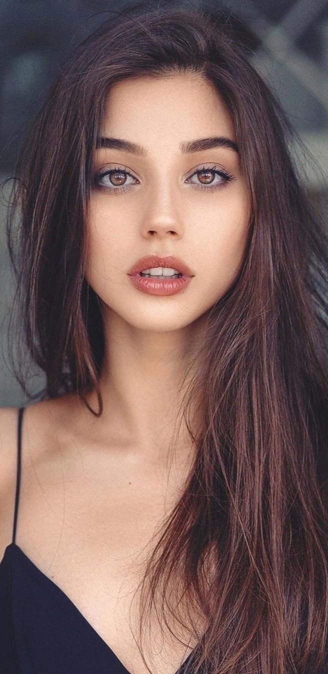 Woman with long brown hair and brown eyes wearing a top with thin straps