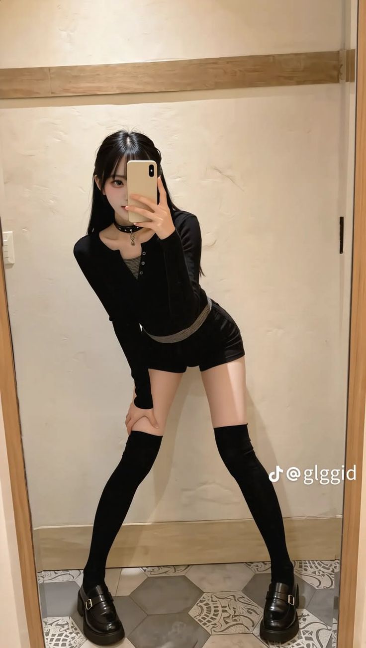 Woman in black top and shorts taking a mirror selfie