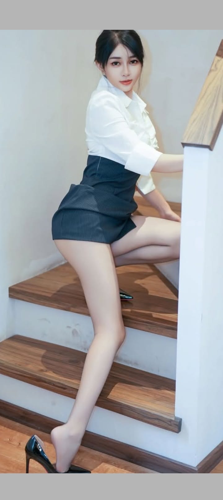 Woman in a white shirt and short skirt posing on stairs