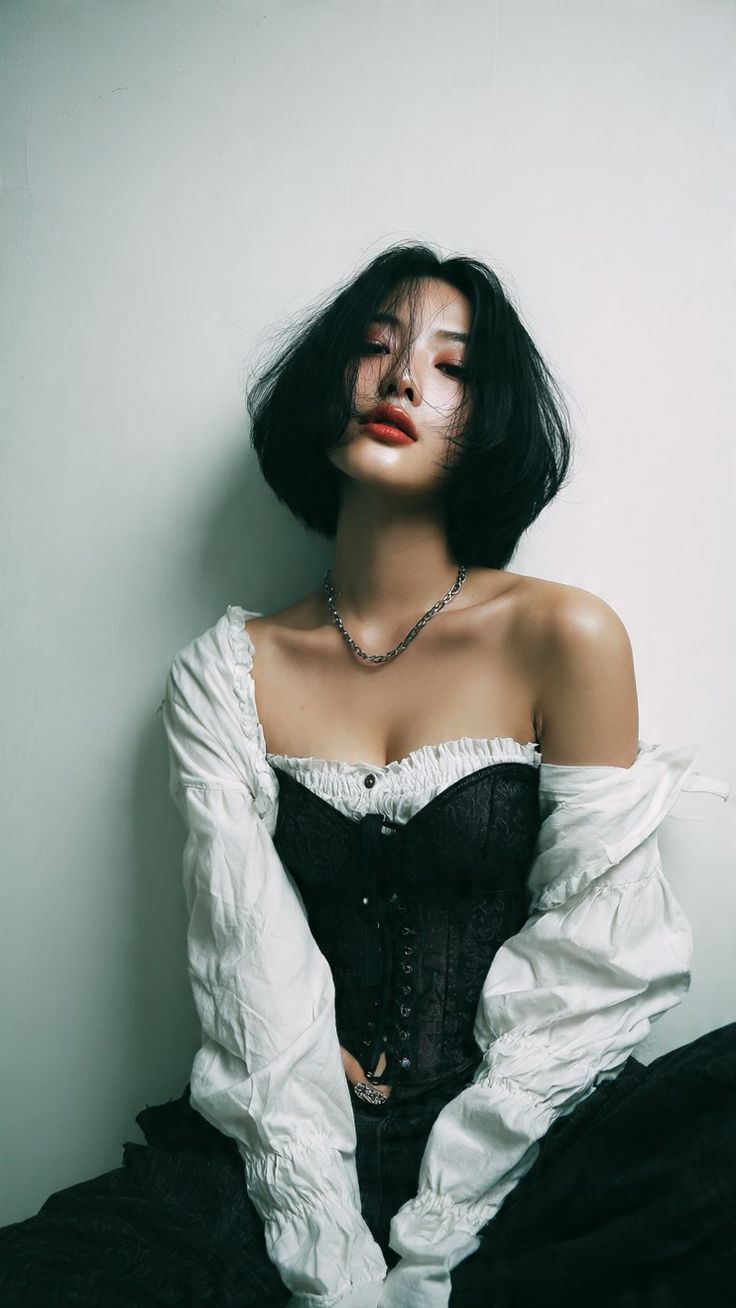 Woman with short black hair wearing a corset and white shirt, looking at the camera