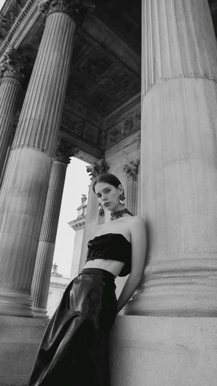 Woman in a strapless top and long skirt posing by classical columns