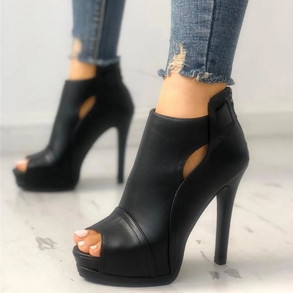 Person wearing black peep-toe ankle boots with ripped jeans