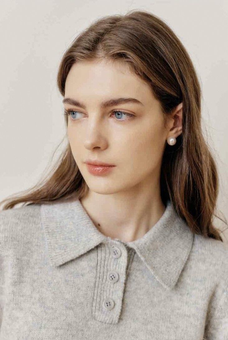 Woman with long brown hair and blue eyes wearing a grey collared sweater