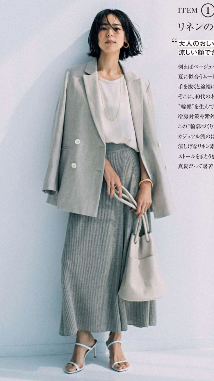 Woman in a light gray blazer and wide leg pants holding a bucket bag