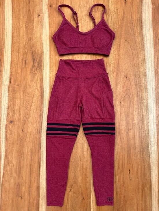 Maroon sports bra and leggings with black stripes on a wooden background