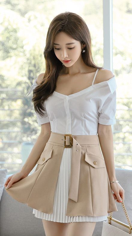 Woman in a white off-shoulder shirt and beige pleated skirt indoors