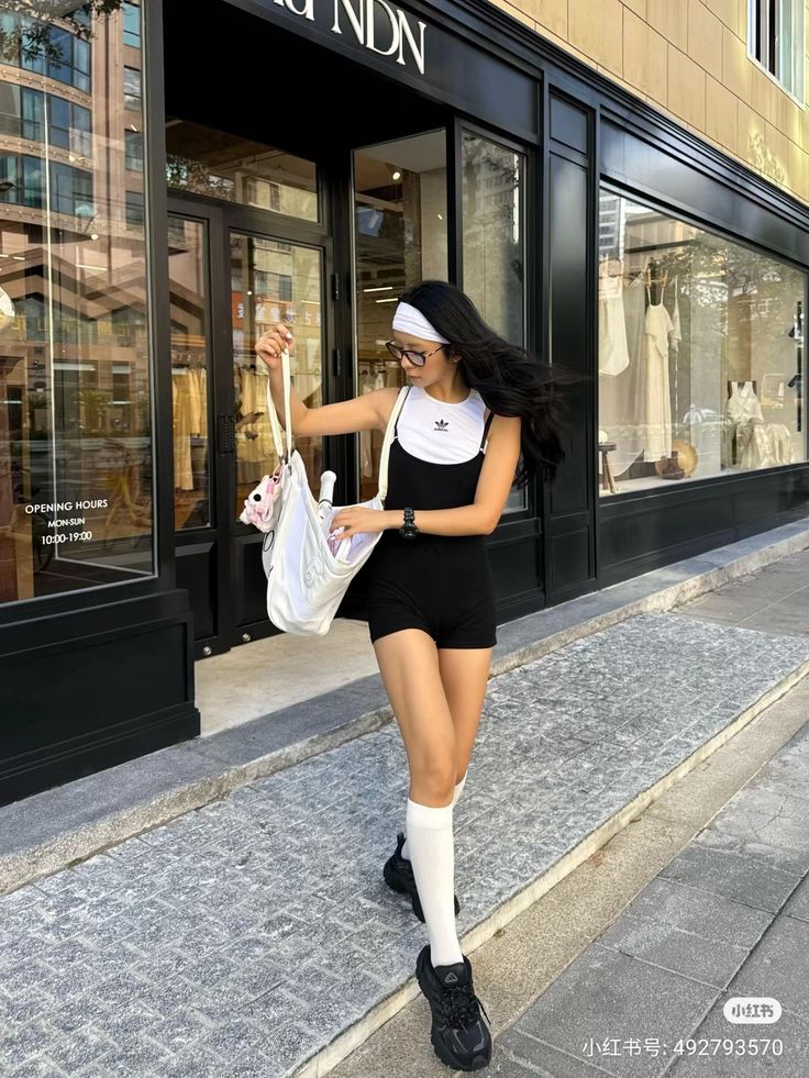 Woman in a black romper and white crop top walking on a street