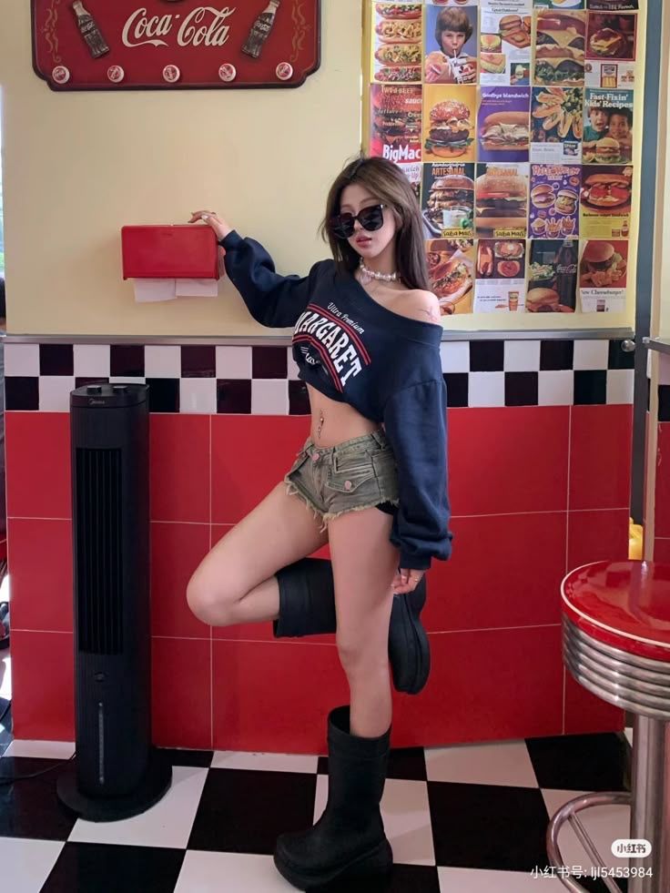Woman in a crop top and denim shorts posing in a retro diner setting