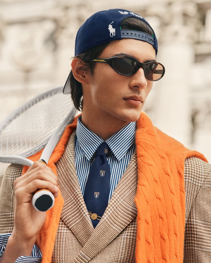 Man in a baseball cap and sunglasses holding a tennis racket