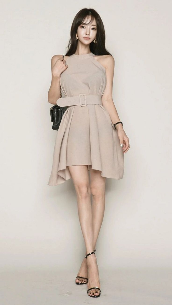Woman in a beige dress and black high heels posing in a studio