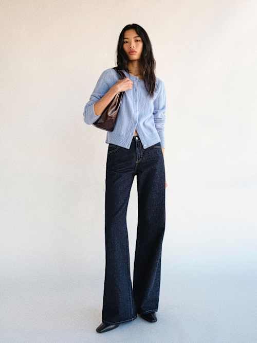 Woman with long hair wearing a light blue cardigan and wide leg jeans