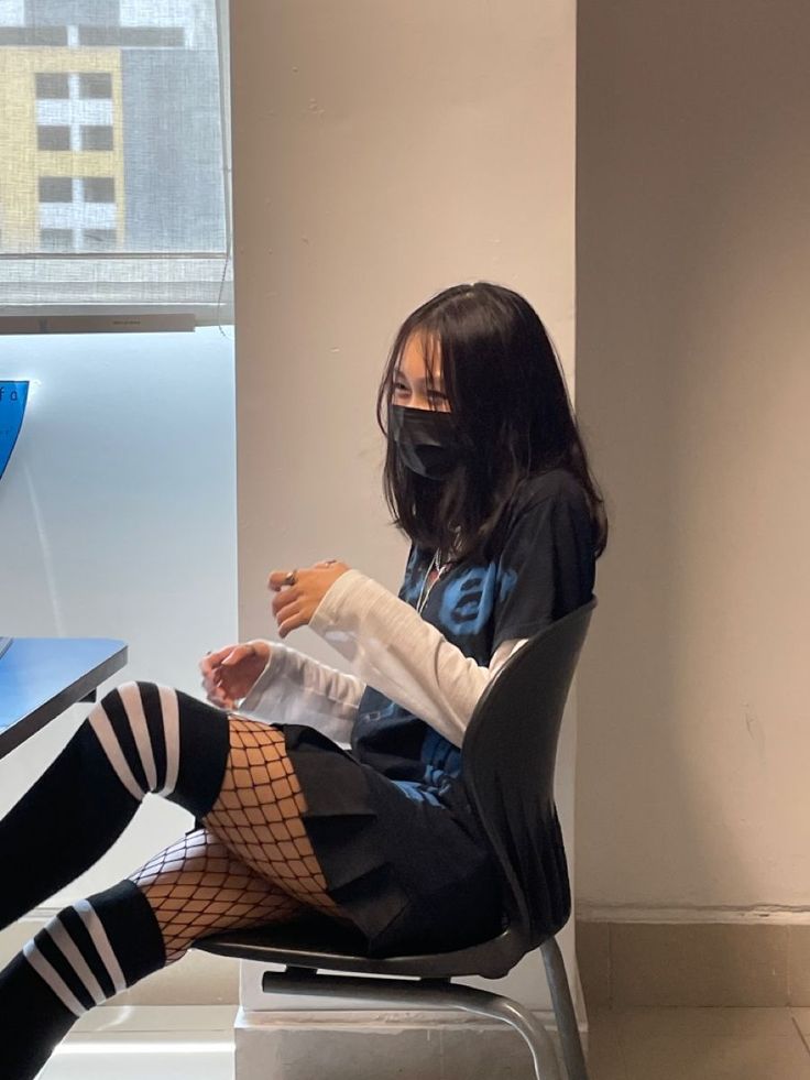 Person with black hair and mask wearing fishnet stockings and striped socks