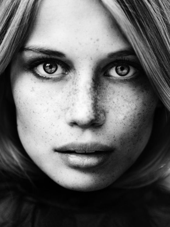 Close up black and white portrait of a woman with freckles and long hair